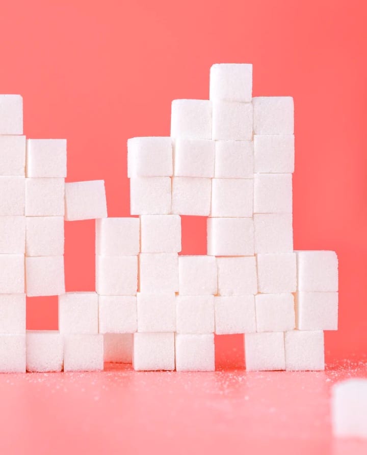 Sugar cubes stacked on the dark pink background